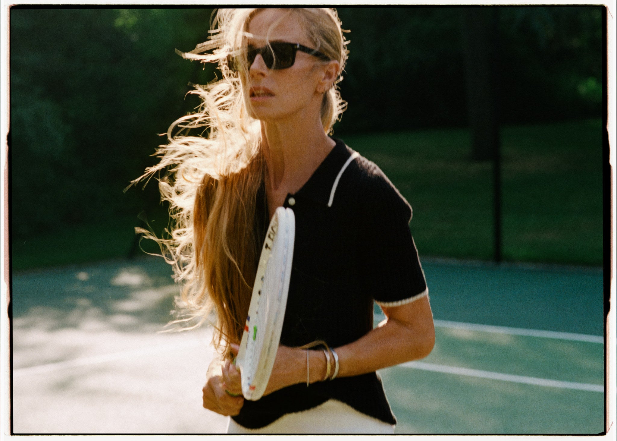 Laura Bailey wearing black knitwear on a tennis court