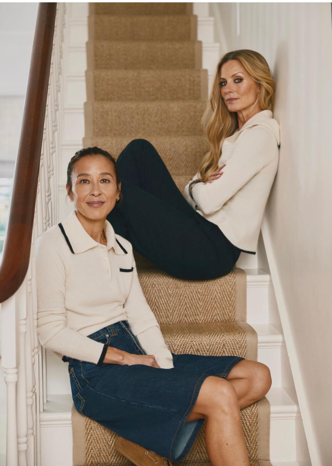 Madeleine Thompson and Laura Bailey sitting on the stairs in cream knitwear
